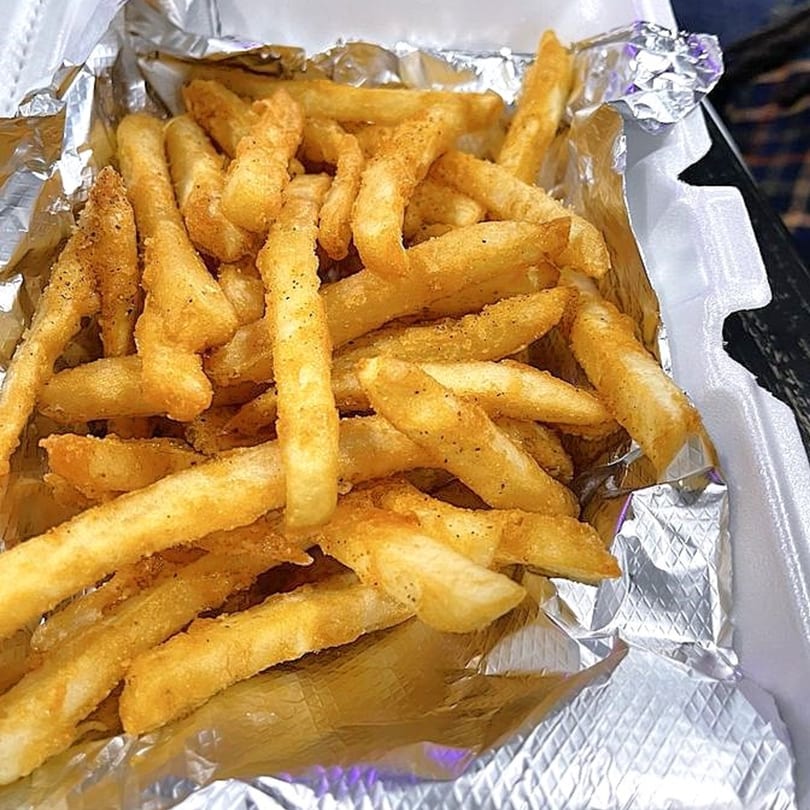 Seasoned french fries in a foil-lined takeout container from Vittles at the PARK.