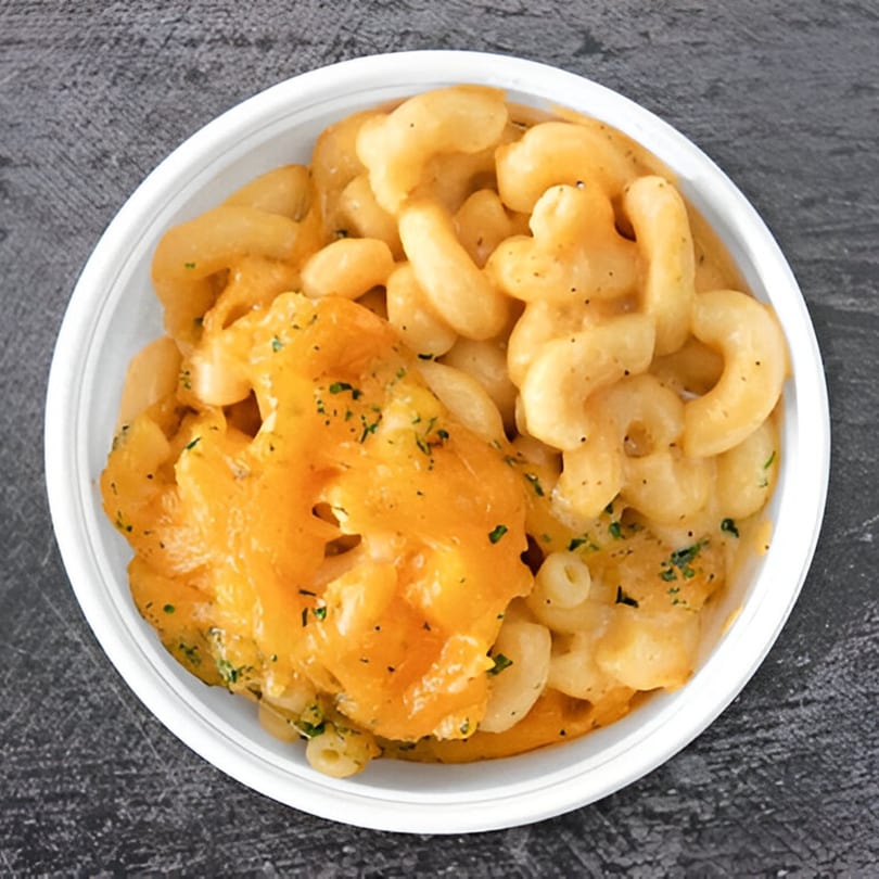 Creamy mac and cheese with melted cheddar and herbs in a white bowl from Vittles at the PARK.